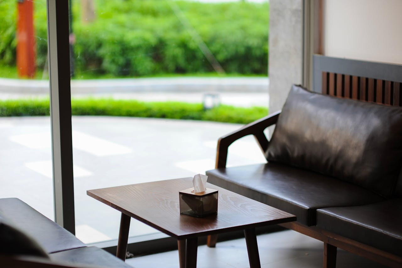 Elegant interior of a modern lounge area featuring leather sofas and a coffee table near large windows.